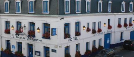 Un edificio blanco con detalles azules, identificado como hotel y restaurante.