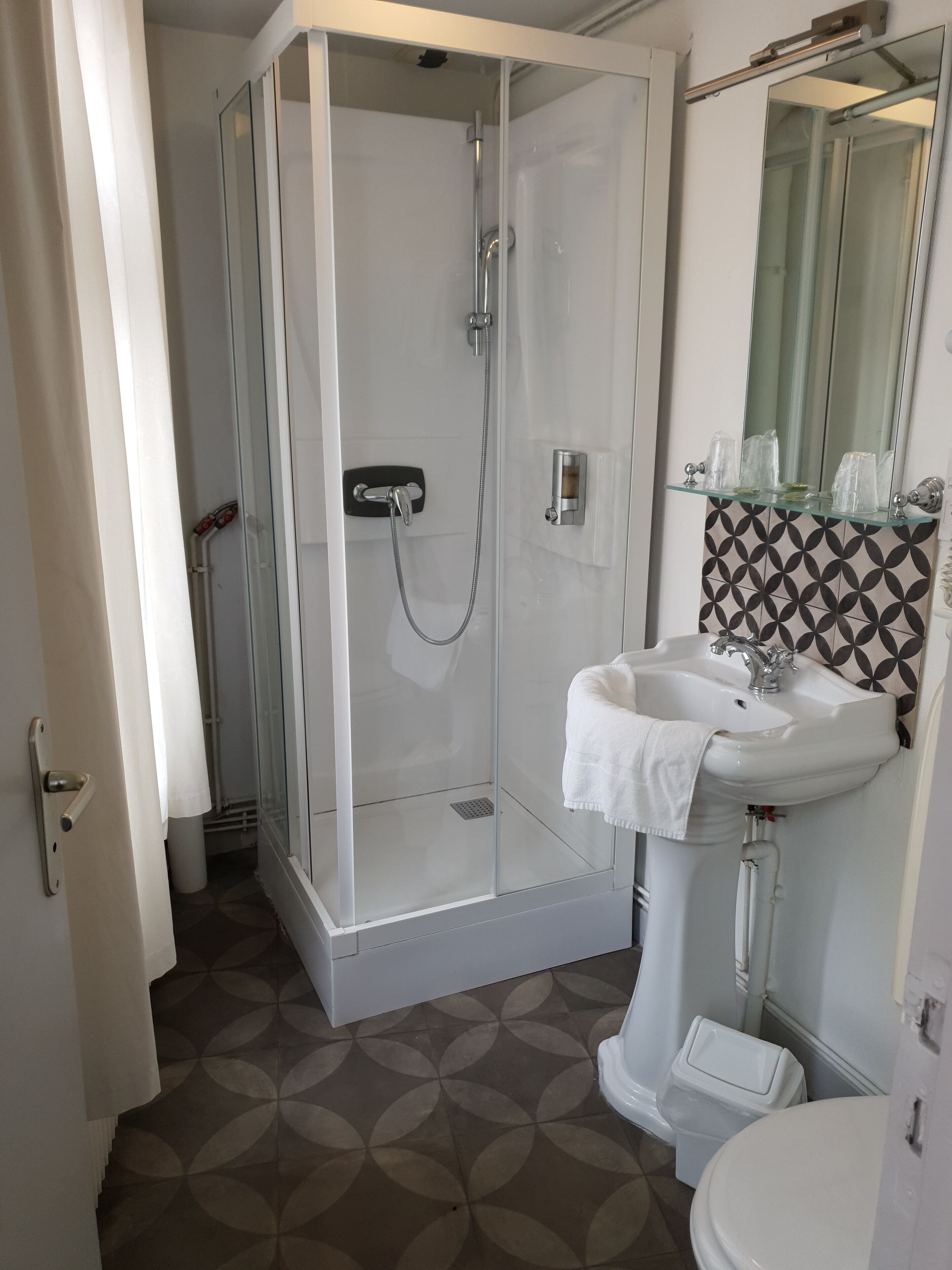 A bathroom with a glass-enclosed shower, a white sink, and a toilet.