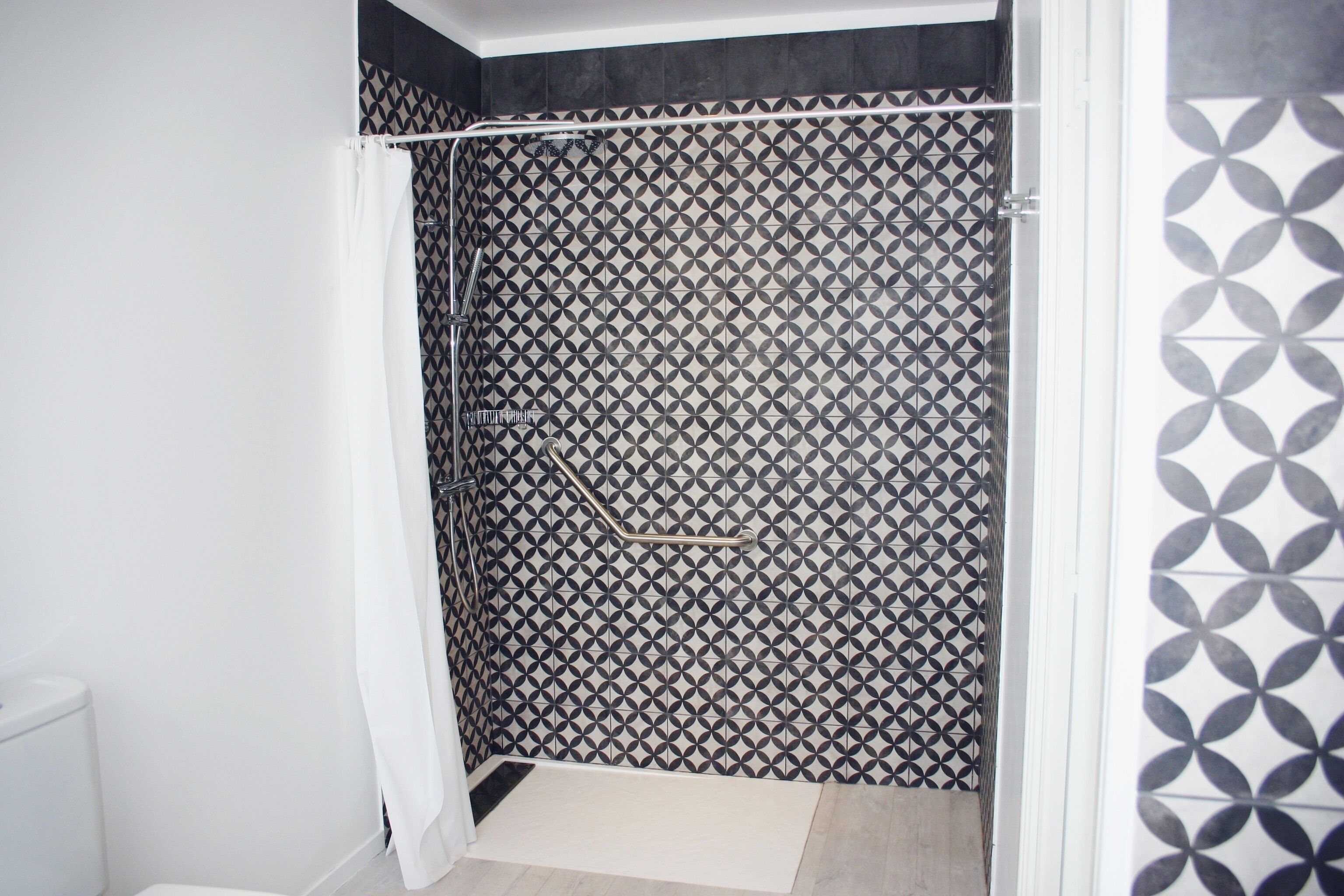 Een badkamer met een douchegedeelte met een geometrisch tegelpatroon.