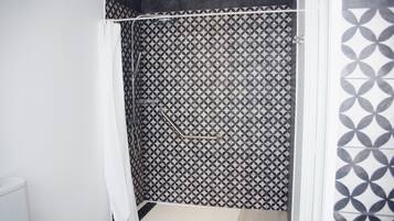Een badkamer met een douchegedeelte met een geometrisch tegelpatroon.