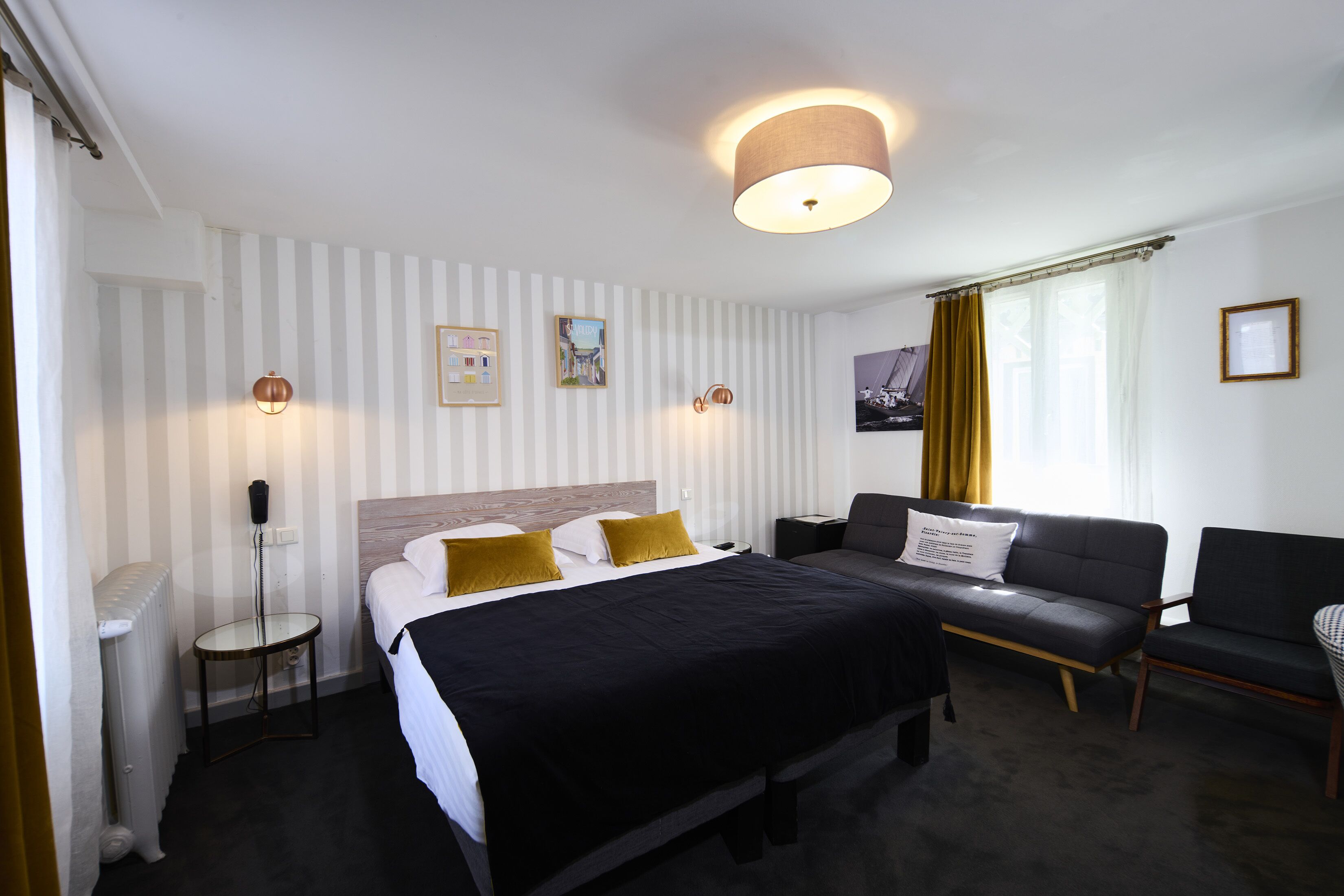 Una habitación de hotel con una cama grande, una mesita de noche, una lámpara, un sofá y una silla.