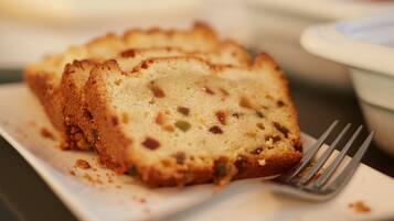 Een plak fruitcake op een wit bord, met een vork ernaast.