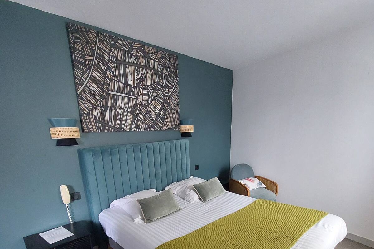 Une chambre à coucher comprenant un lit, une table de chevet, une lampe et une œuvre d’art murale.