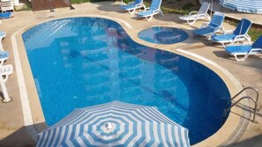 Alberca al aire libre, sombrillas en la alberca y camastros 