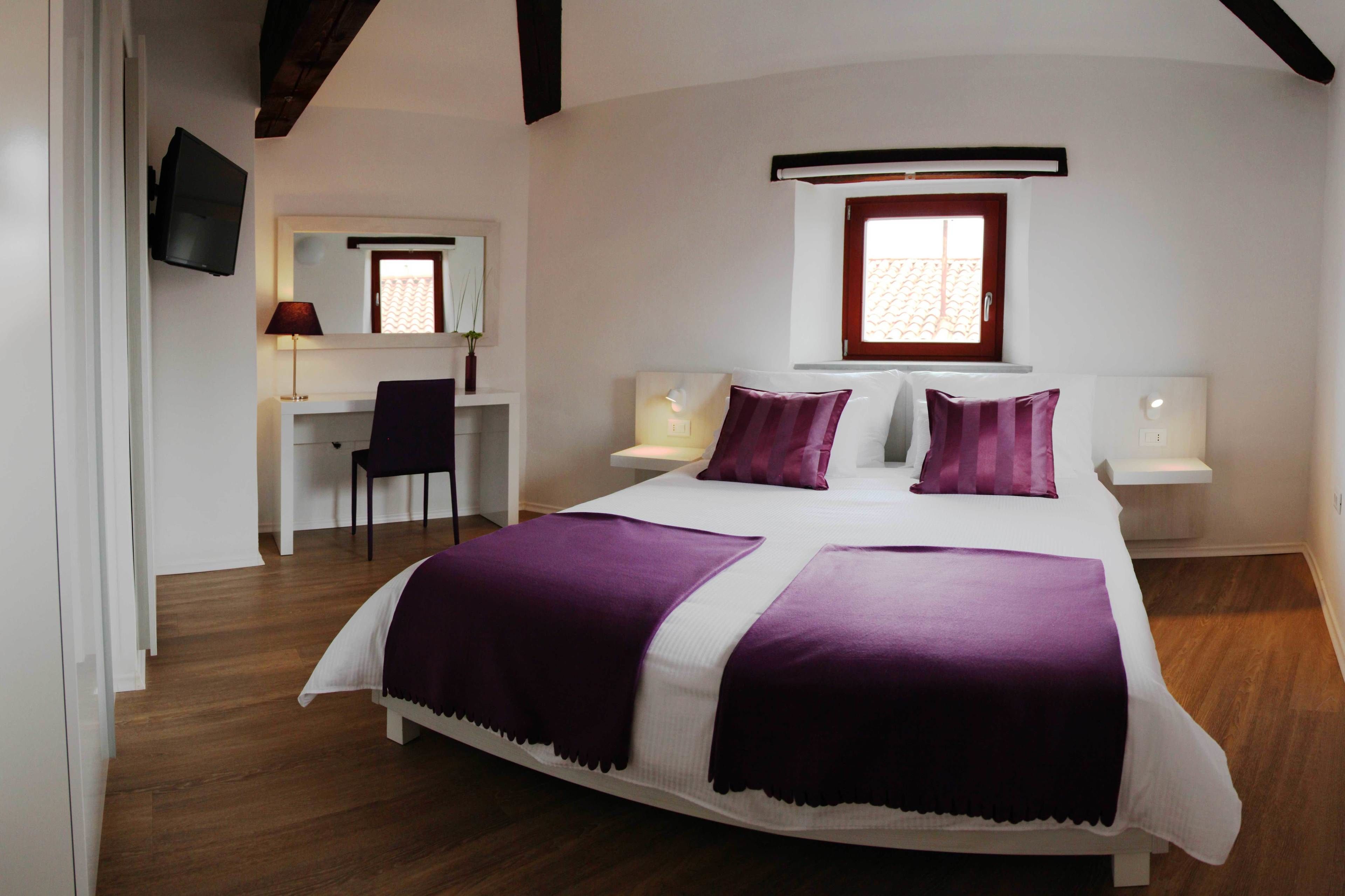 A bedroom with a large bed, two bedside tables, a desk, and a chair.
