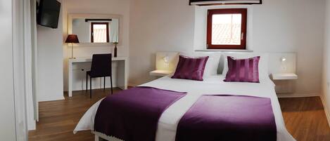 A bedroom with a large bed, two bedside tables, a desk, and a chair.