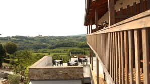 A balcony with a stone wall, wooden railing, and outdoor furniture. - Boutique Hotel Dvor (Brda)