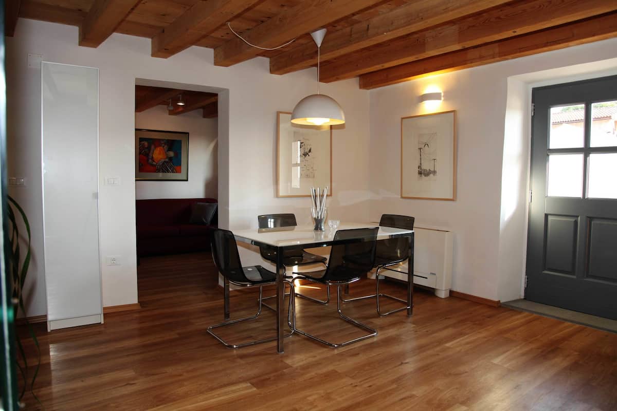 A dining area with a wooden floor, a white table, black chairs, and framed artwork on the walls.
