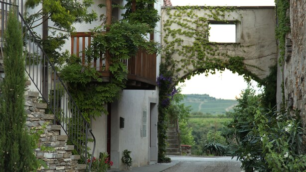 A narrow street with a stone staircase leading to a building with a wooden balcony. - Boutique Hotel Dvor (Brda)