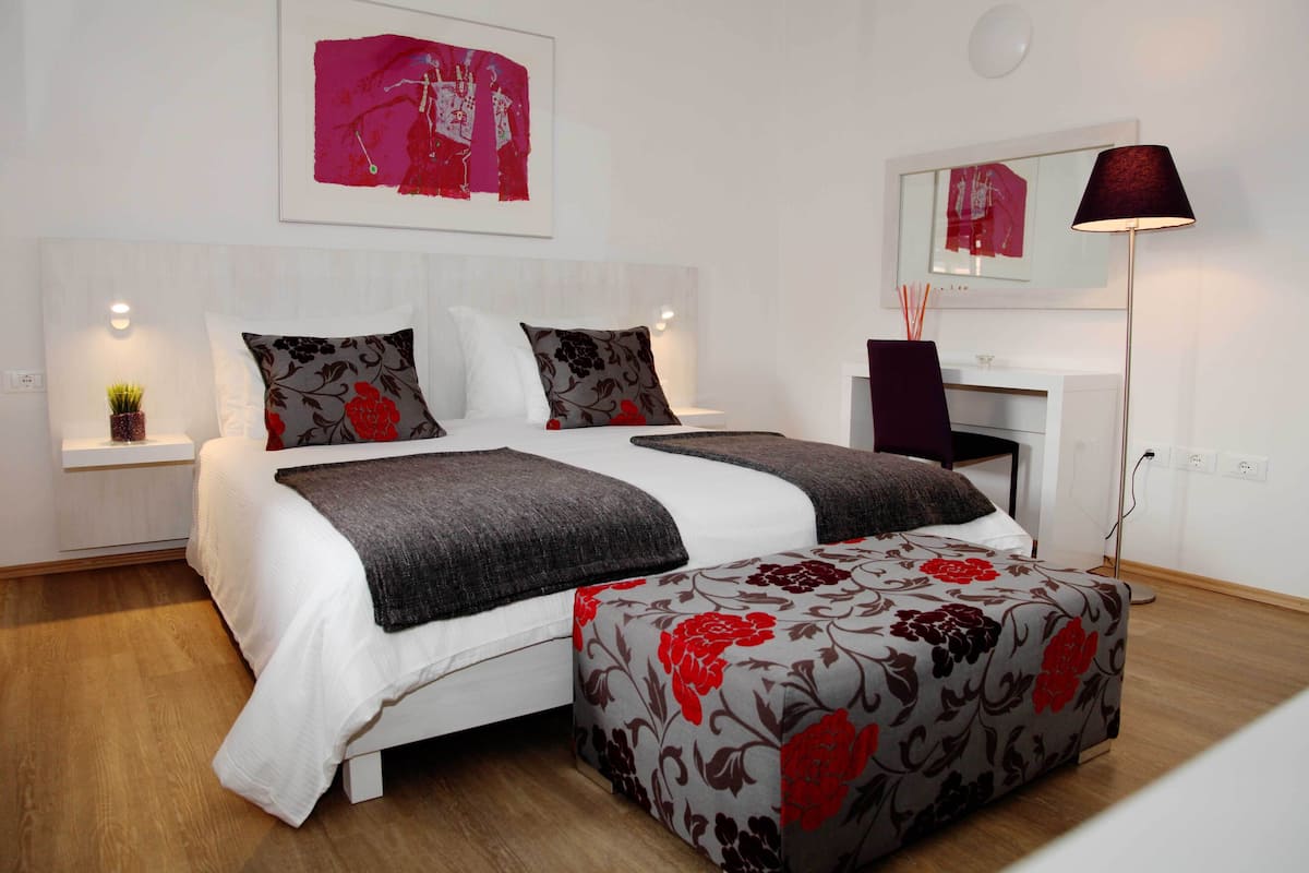 A neatly arranged bedroom with a large bed, bedside tables, a bedside lamp, and a mirror on the wall.