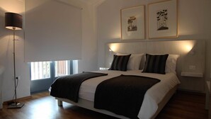 A modern bedroom with a large bed, a standing lamp, and two framed pictures on the wall. - Boutique Hotel Dvor (Brda)