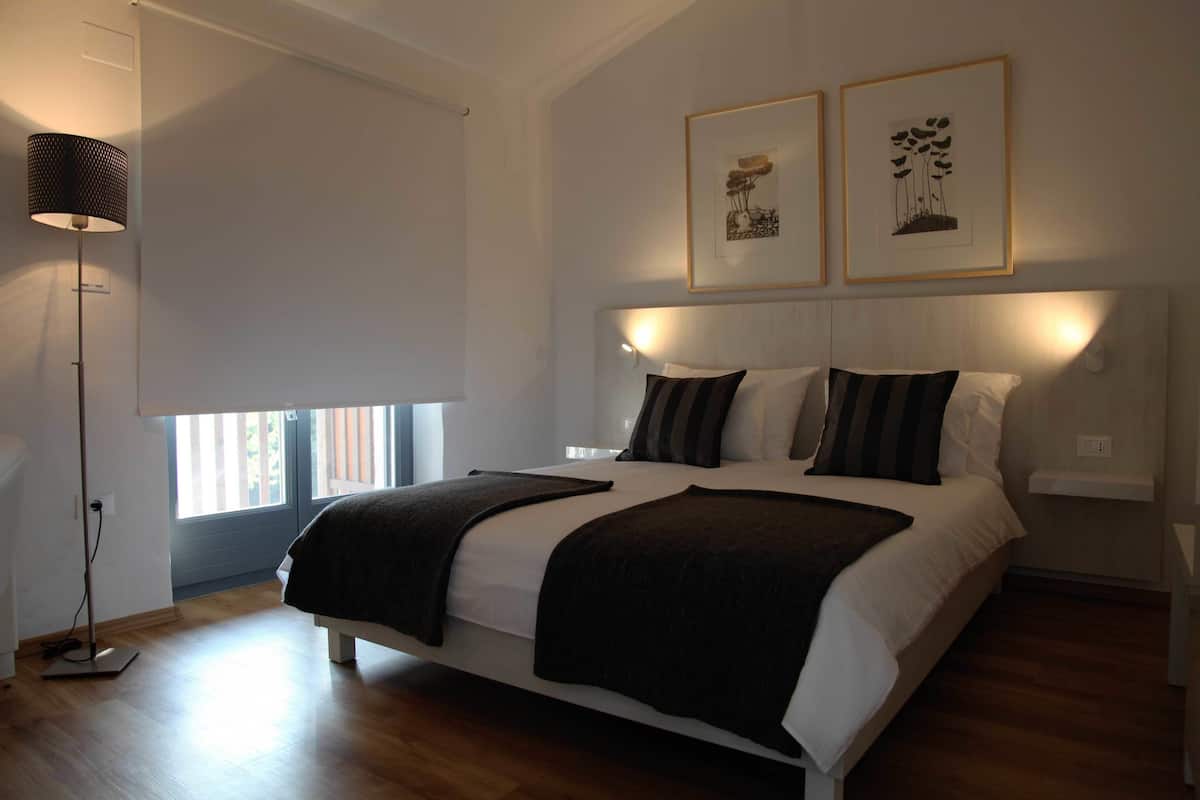 A modern bedroom with a large bed, a standing lamp, and two framed pictures on the wall.