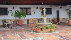 A courtyard with a fountain, potted plants, and outdoor furniture. - Hotel León Dorado (Bucaramanga)