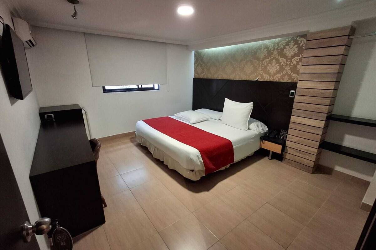 Ein Hotelzimmer mit einem Bett, einem Schreibtisch, einem Nachttisch und einem Fenster.