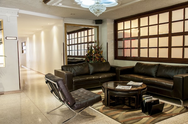 Un moderno vestíbulo con un sofá de cuero marrón, una mesa de centro de vidrio y un sillón de cuero.