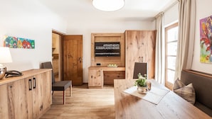 A modern, well-lit room with wooden furniture, a desk, and a dining area. - Appartement Ausserladscheider (Leutasch)