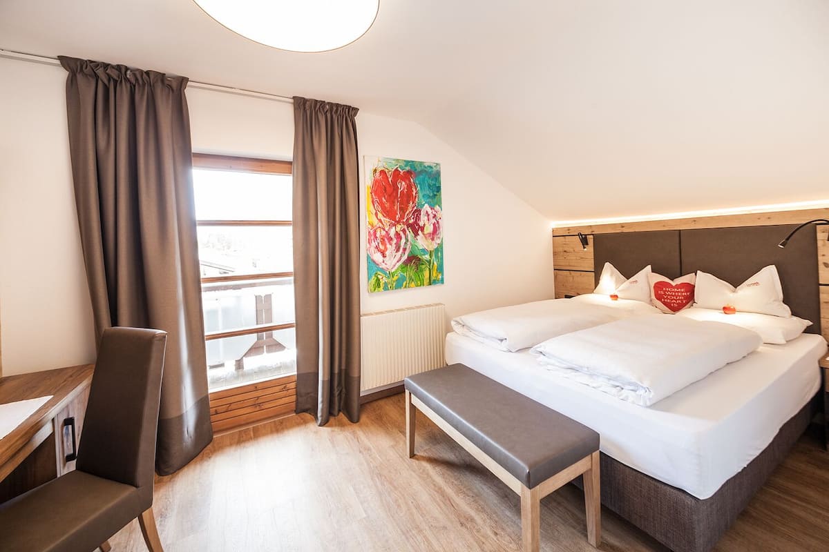 Une chambre d’hôtel avec un lit, un banc, un bureau et une chaise.