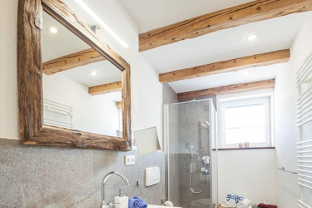 Une salle de bain moderne avec un grand miroir, un lavabo, une douche et des toilettes.