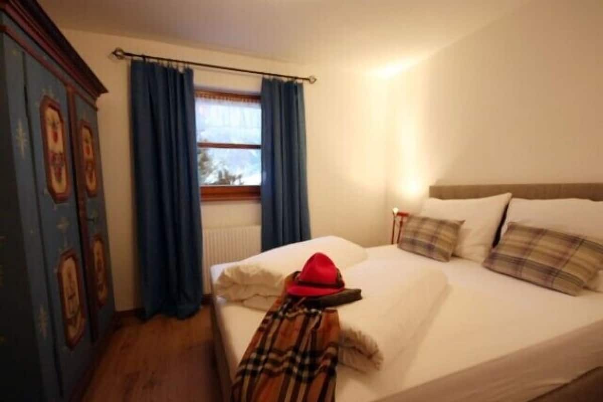 Une chambre à coucher avec un lit, un chapeau rouge et une couverture à carreaux.