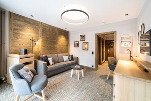 A modern living room with a sofa, armchairs, a coffee table, and a wooden accent wall. - Hotel OTP Birkenhof (Bad Kleinkirchheim)