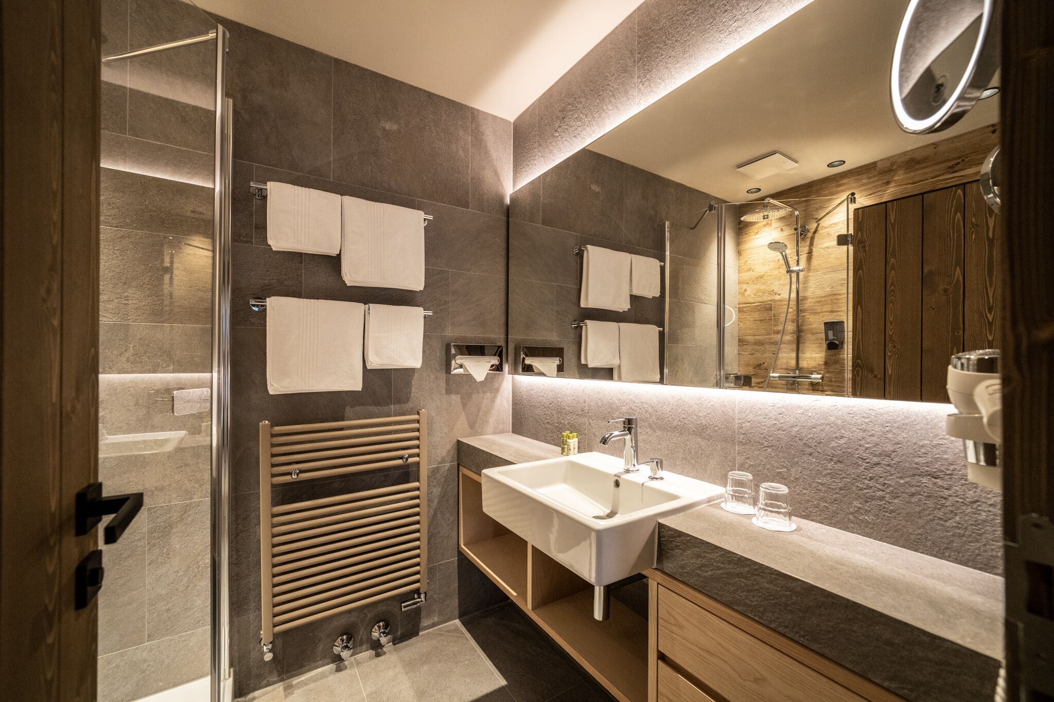 Un baño moderno con cabina de ducha de vidrio, un espejo grande y un lavamanos empotrado con tocador.