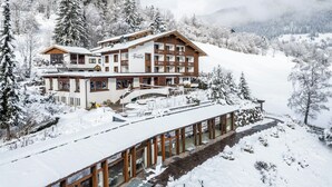 A multi-story hotel with a ski lift, surrounded by snow-covered trees and mountains. - Hotel OTP Birkenhof (Bad Kleinkirchheim)