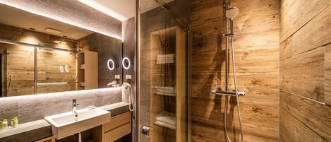 A modern bathroom with a glass-enclosed shower, a vanity with a sink, and a large mirror.
