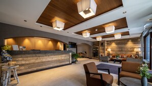 A modern lobby with a reception desk, seating area, and wooden accents. - Hotel OTP Birkenhof (Bad Kleinkirchheim)
