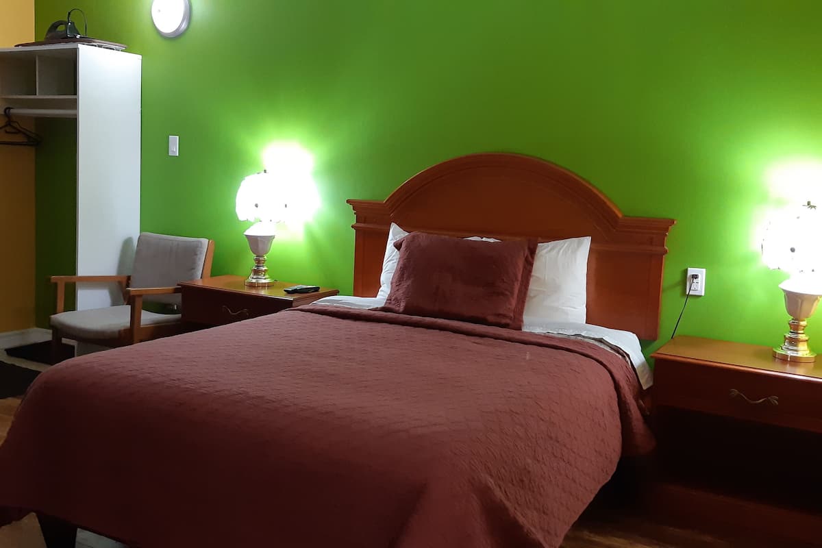 A room with a bed, bedside tables, a chair, and a wardrobe.