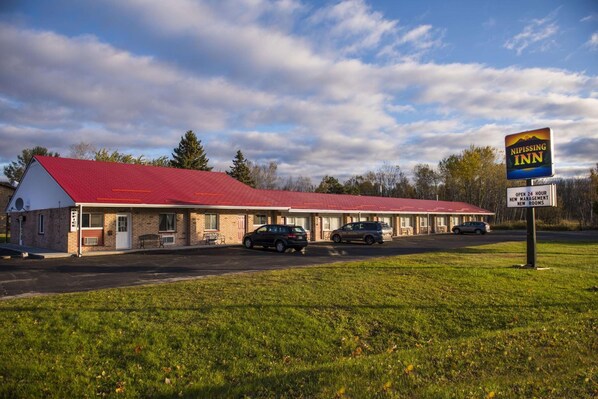 Un motel con techo rojo, varias habitaciones y un cartel que anuncia habitaciones nuevas.