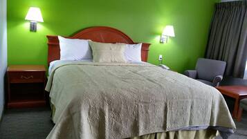 Une chambre d’hôtel avec un lit, deux lampes de chevet, une table de chevet, une chaise et une fenêtre avec des rideaux.