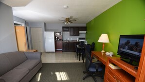 A compact living space with a kitchenette, a dining area, and a seating area with a television. - Nipissing Inn (North Bay)