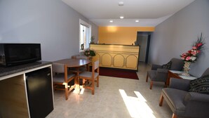 A compact living space with a kitchen area, dining table, and seating arrangement. - Nipissing Inn (North Bay)