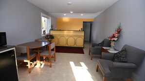 A compact living space with a dining area, a sofa, a small table, and a kitchenette. - Nipissing Inn (North Bay)