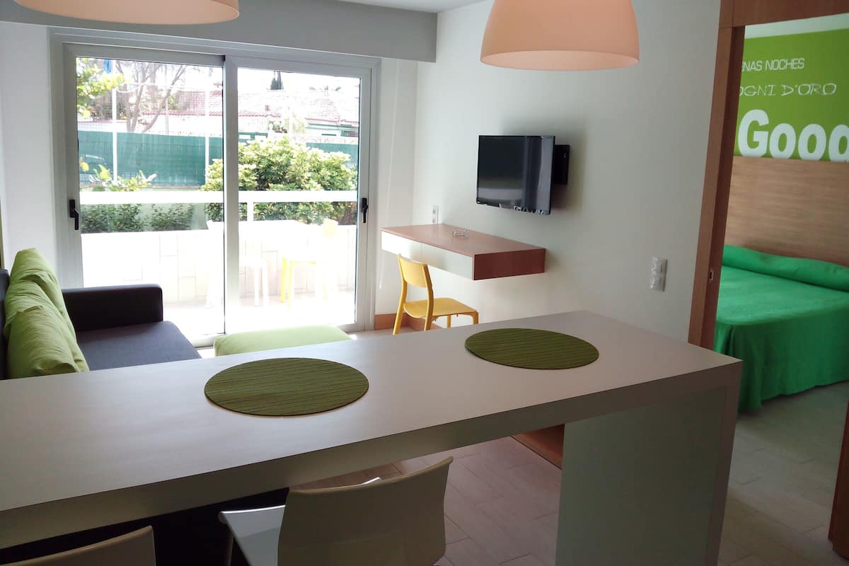 Eine moderne Küche mit Essbereich, einem an der Wand montierten Fernseher und Blick auf den Balkon.