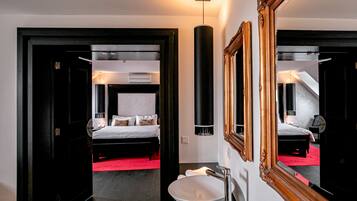 Una habitación de hotel moderna con una cama grande, un espejo redondo y un lavamanos blanco.