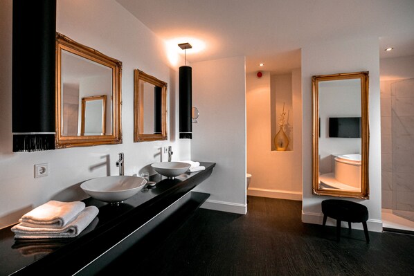A modern bathroom with two sinks, a large mirror, and a black vanity. - Le Theatre Hotel (Maastricht)