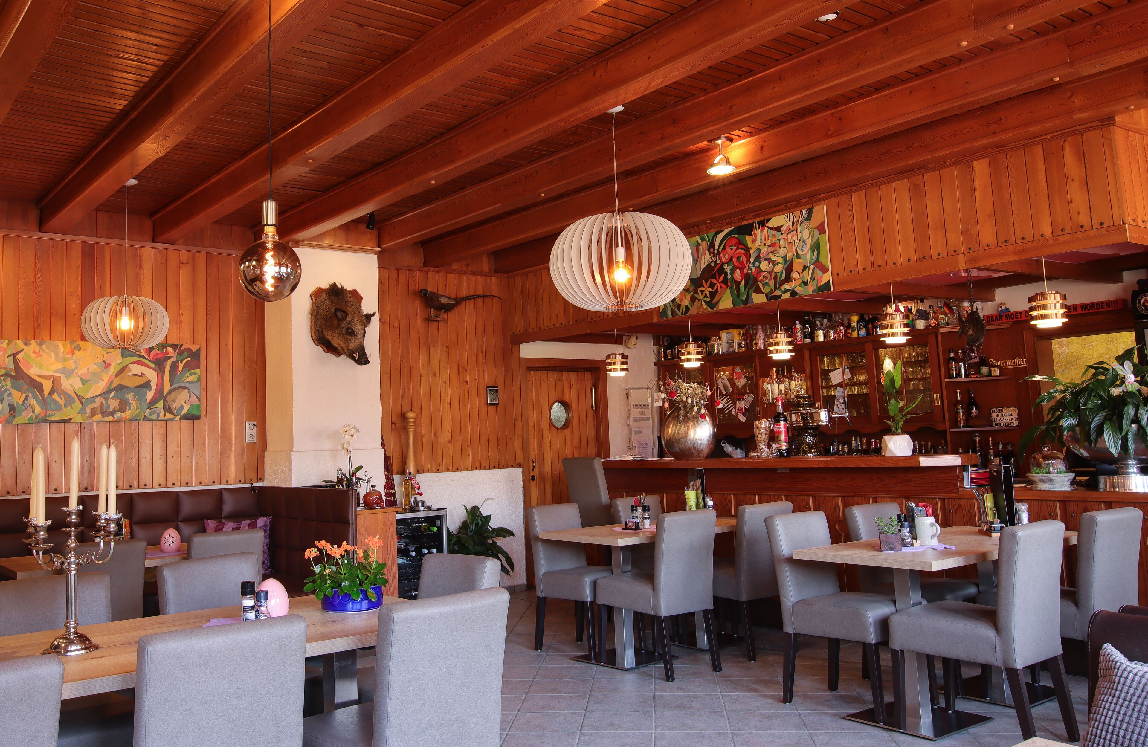 Un restaurante con paredes de madera, varias mesas y lámparas colgantes.