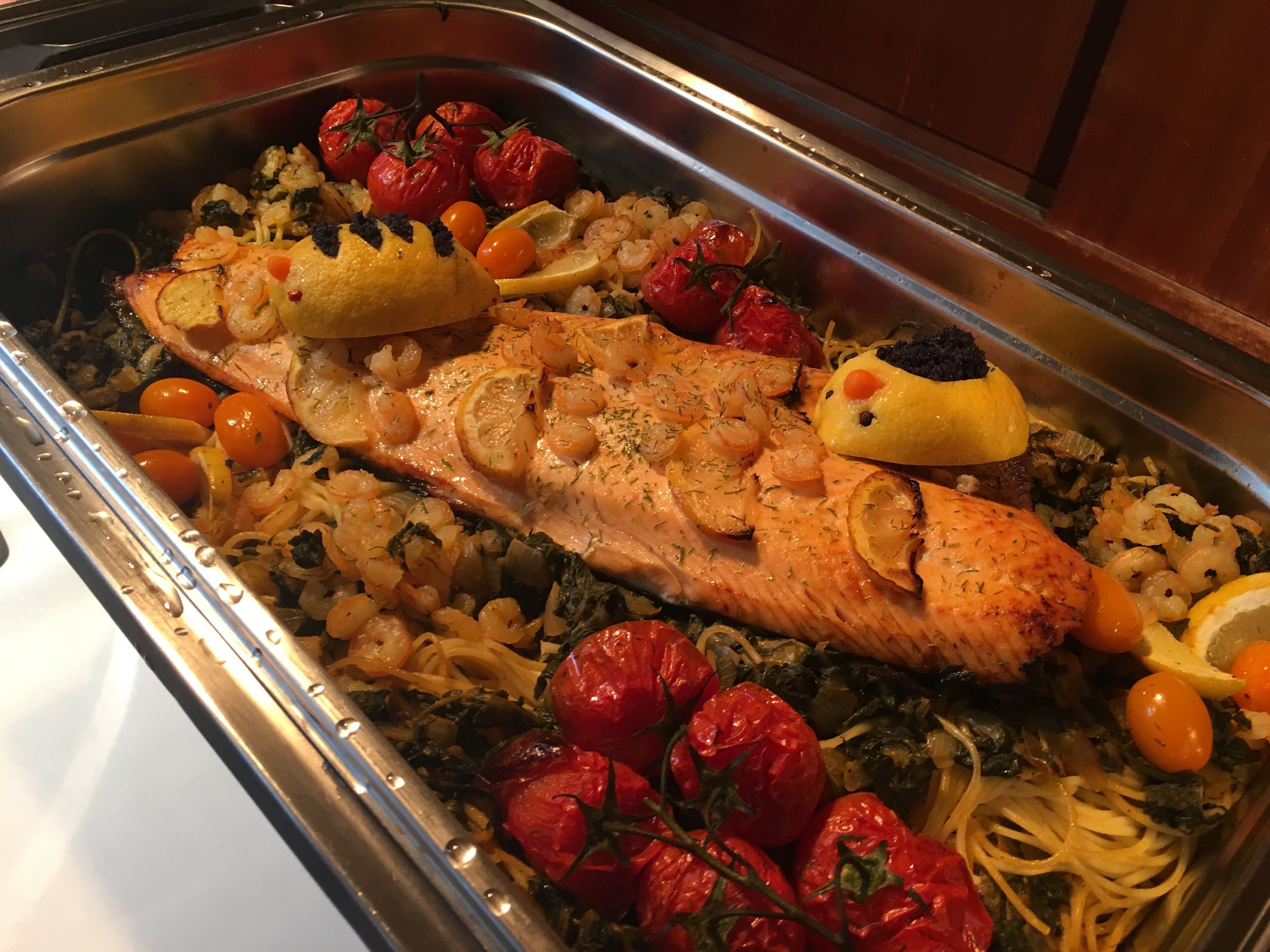 A buffet with a variety of dishes including salmon, shrimp, and vegetables.