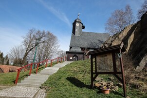 Una iglesia con una torre del reloj, una escalera roja y un cartel.