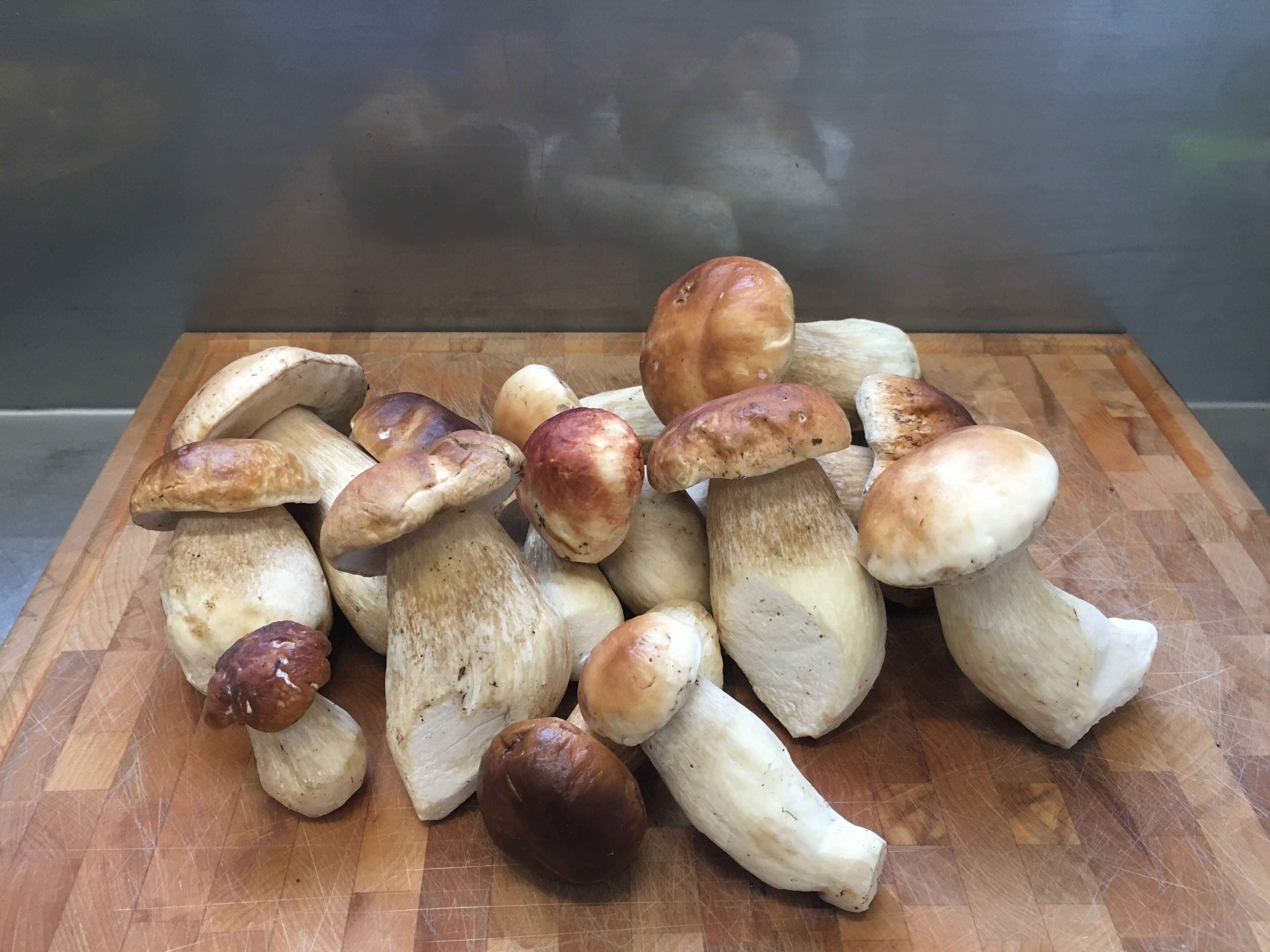 A wooden cutting board with a pile of mushrooms.