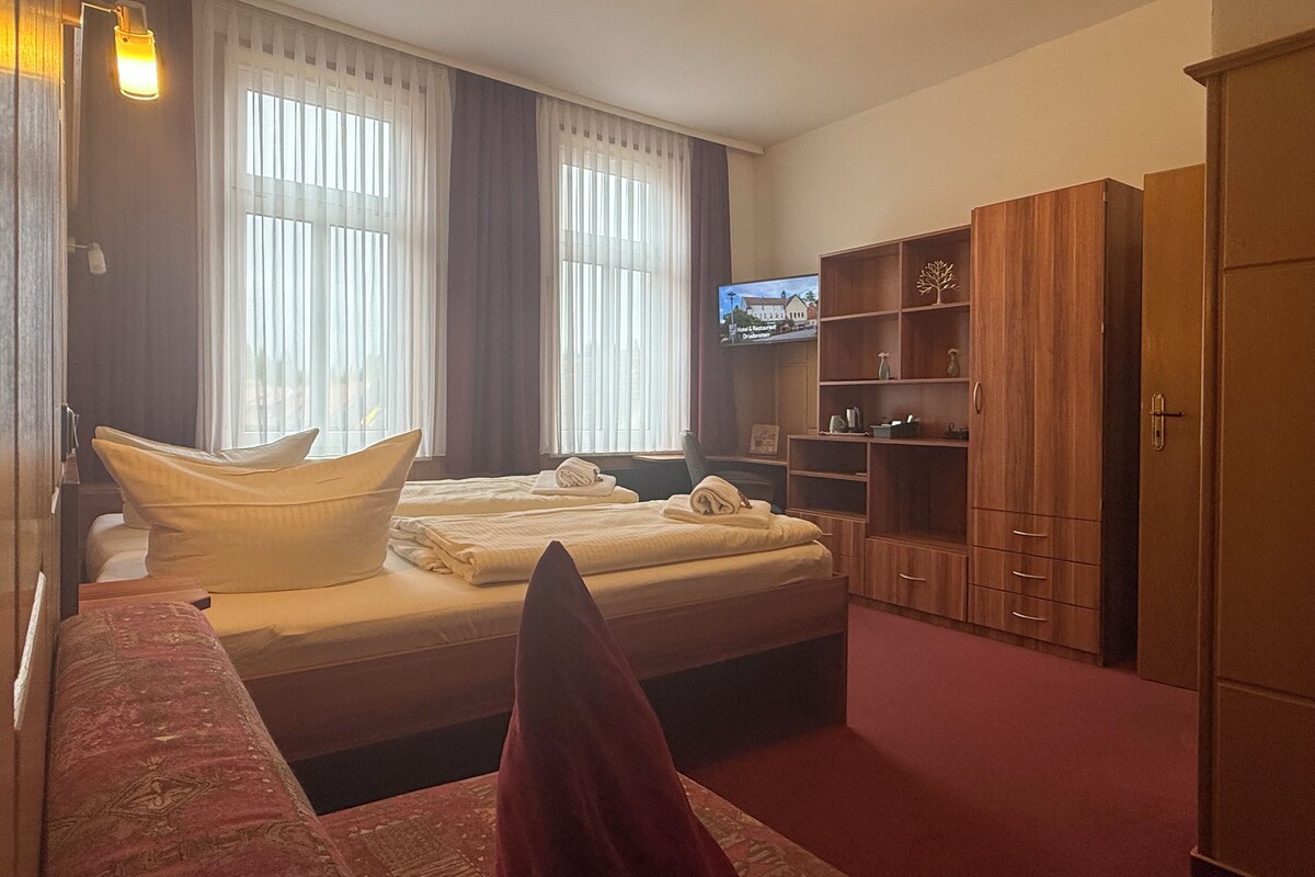 Ein Hotelzimmer mit einem Bett, einem Fernseher, Holzmöbeln und Teppichboden.