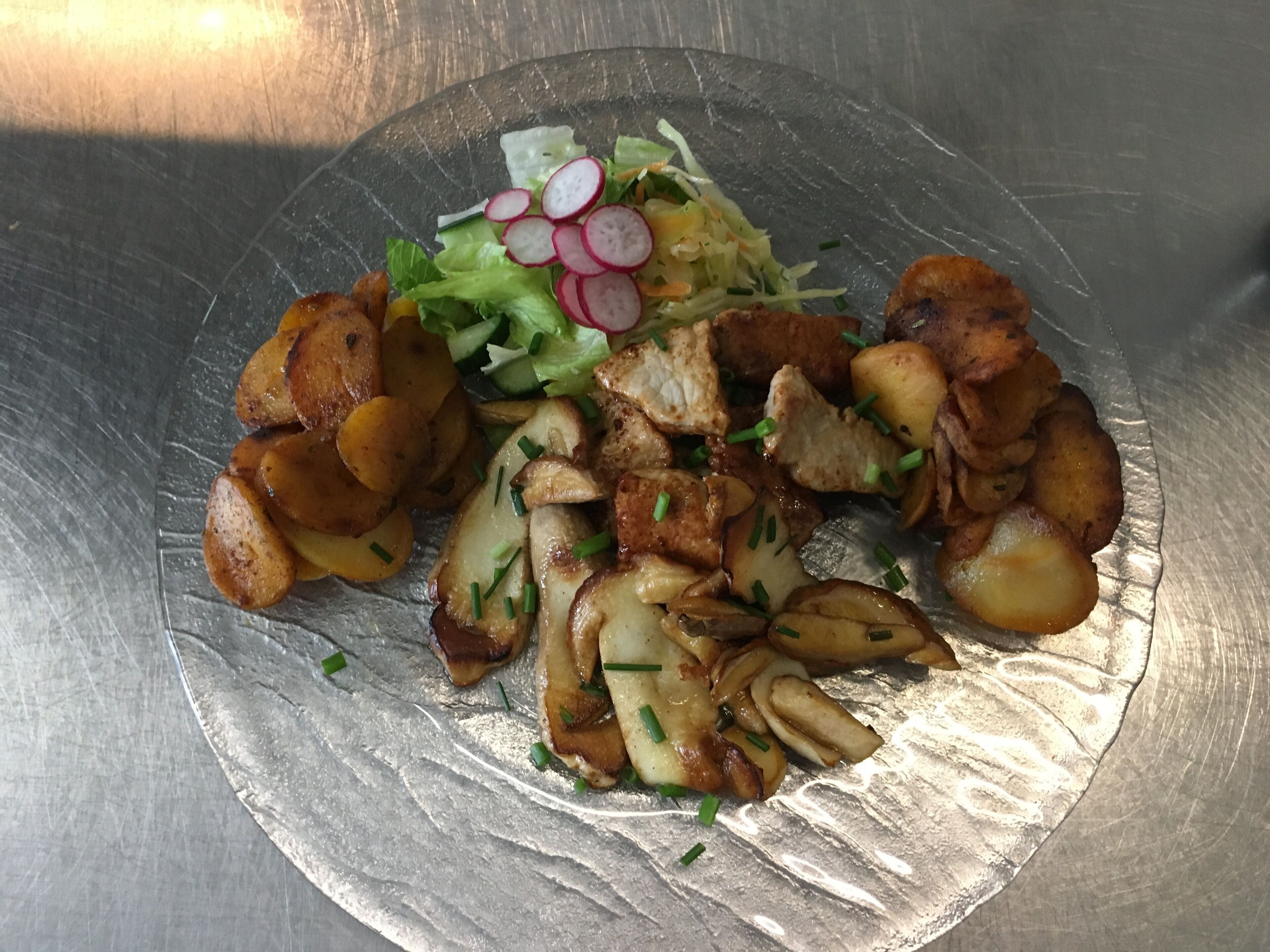 Un plato de comida con patatas asadas, carne y una ensalada.