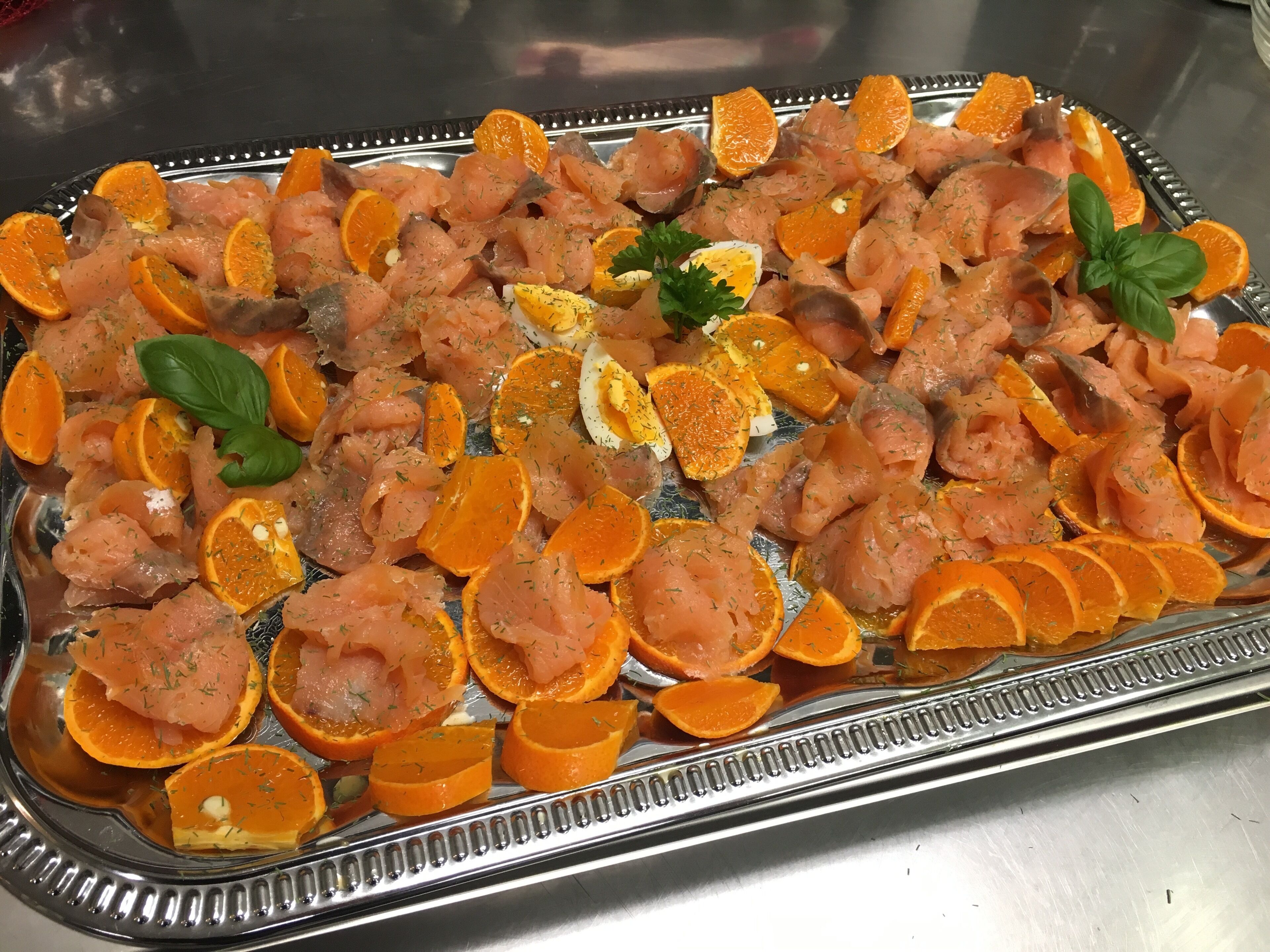 A tray of food with salmon, orange slices, and garnishes.