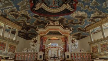 Interno di una chiesa decorata, con soffitto a volta, affreschi dettagliati e un altare centrale.
