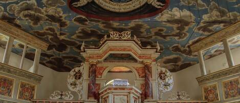 An ornate church interior with a high ceiling, detailed frescoes, and a central altar.