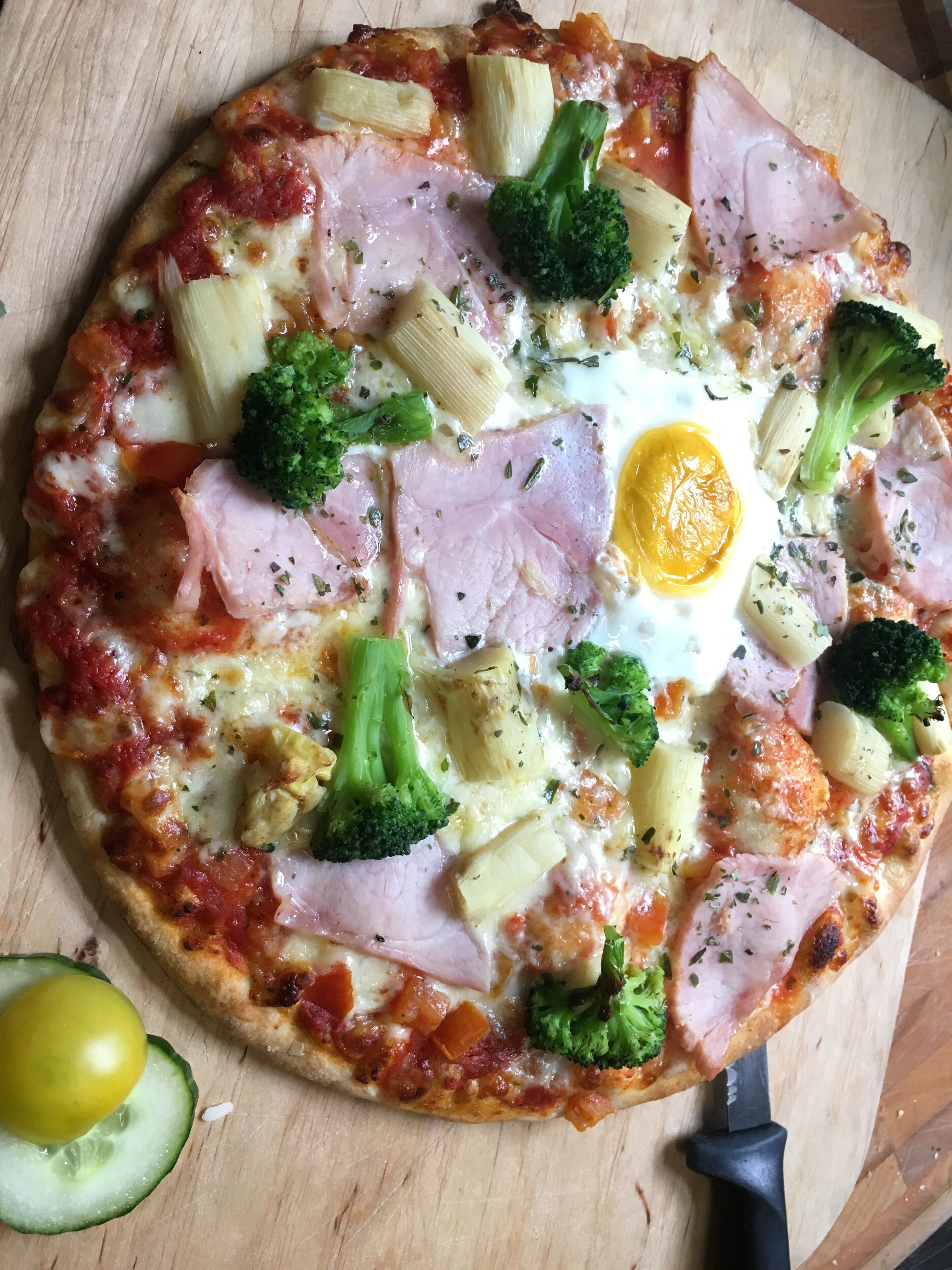 Una pizza amb diferents ingredients sobre una taula de fusta.