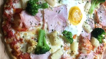 Una pizza amb diferents ingredients sobre una taula de fusta.