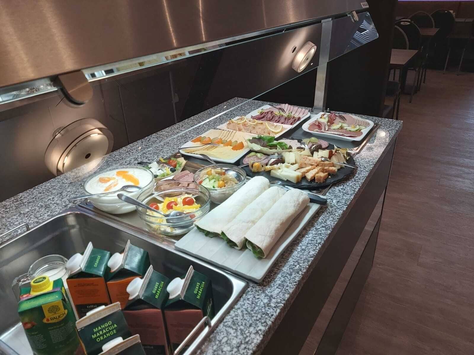 A buffet with various food items, including salads, meats, and beverages.