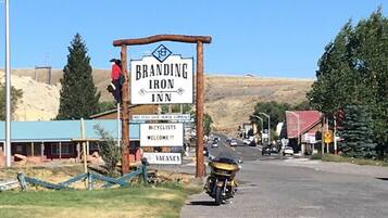 A sign for Branding Iron Inn with a clear view of the surrounding area, including a gravel road and a parked motorcycle.